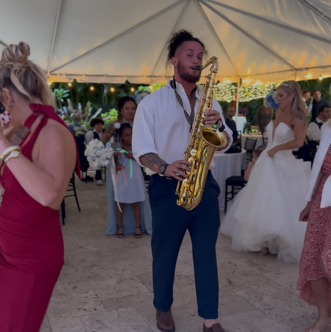 A saxophonist performing among wedding guests on the dance floor
